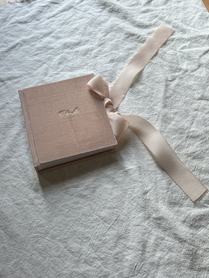 A vintage pink photo album with ribbon tied on soft white fabric, perfect for intimate memories.