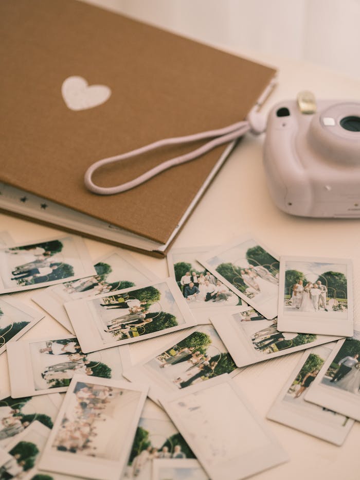 A collection of polaroid photos scattered with an instant camera and album on a white surface.